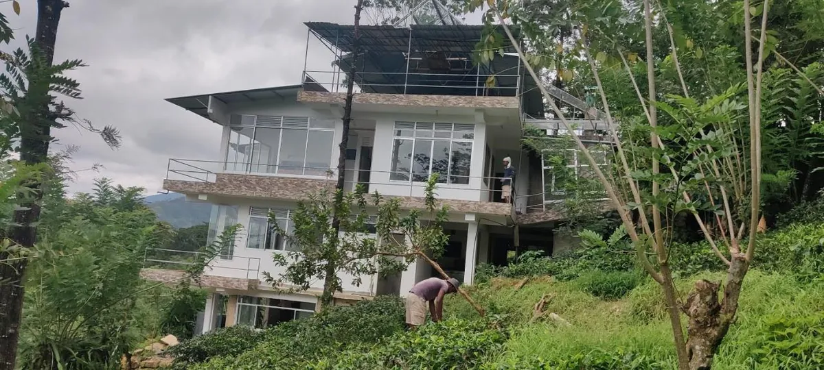 The bungalow among tea bushes and trees, mountains behind